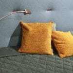 Kolorowe poduszki na łóżku oświetlone lampą w sypialni do czytania