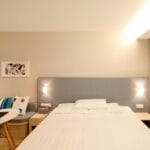 Nowoczesna sypialnia hotelowa z nastrojowym oświetleniem do czytania