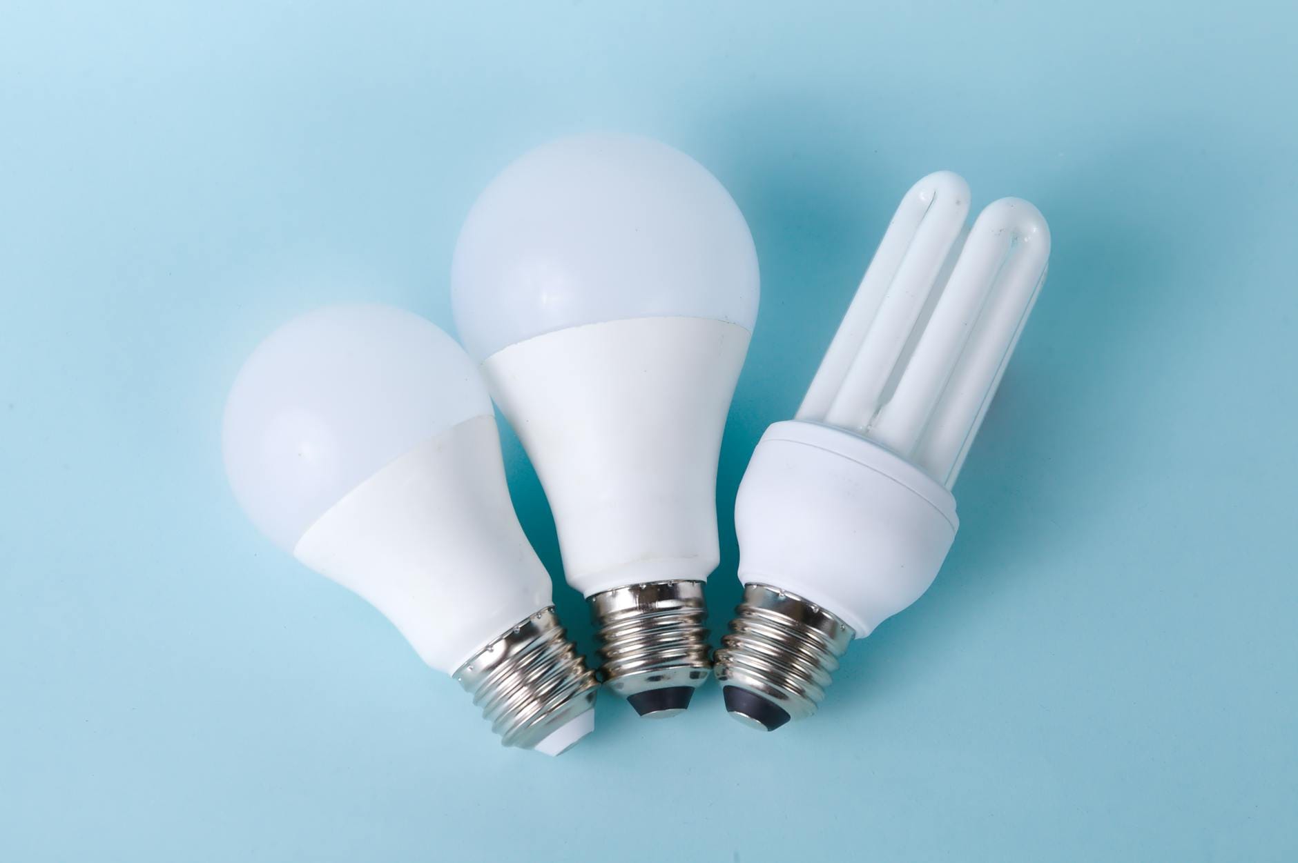 Trzy różne żarówki LED i CFL na jasnoniebieskim tle